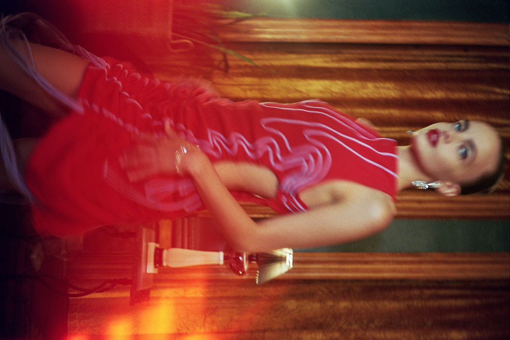 Person wearing an adjustable red dress with lavender embroidery in an art deco room speakeasy. Dress is adjustable. Can be midi, maxi, side slit, or mini. Weddings, Cocktail, Romantic, colorful, statement piece